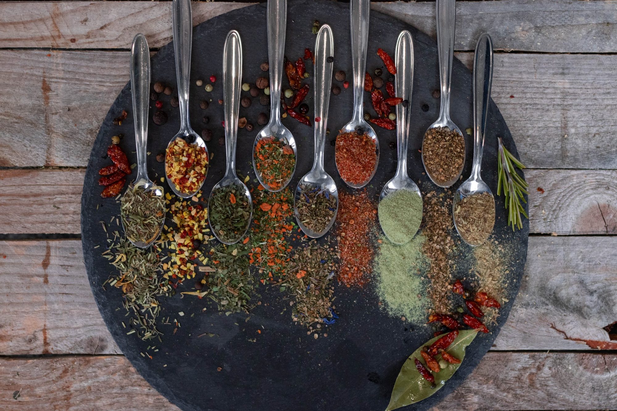 Aromatische Gewürzmischungen auf Löffeln und einer Schieferplatte